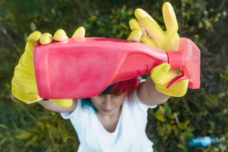 Femme avec des gants jaunes tenant une bouteille