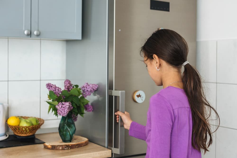Fille ouvrant le frigo dans la cuisine